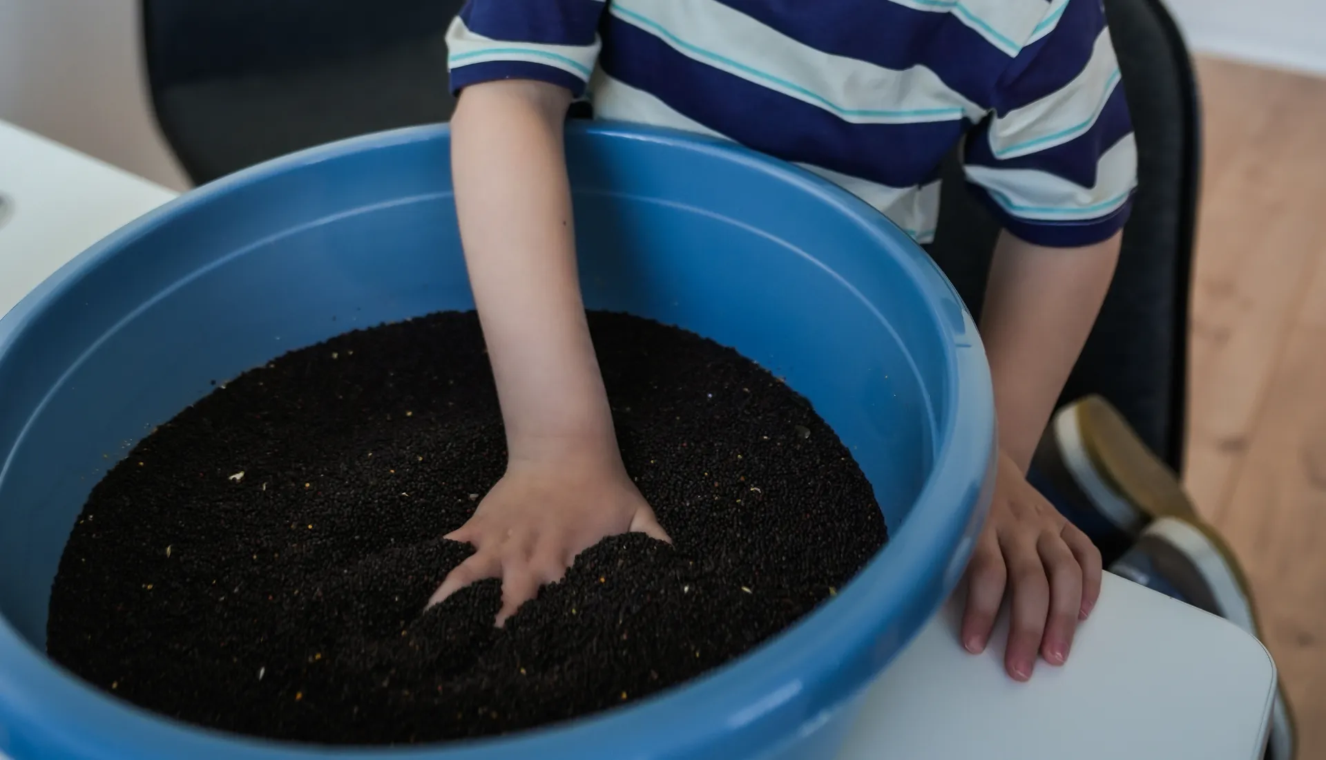 Kinderhand in einer Fühlkiste – sensorische Übung in der Ergotherapie